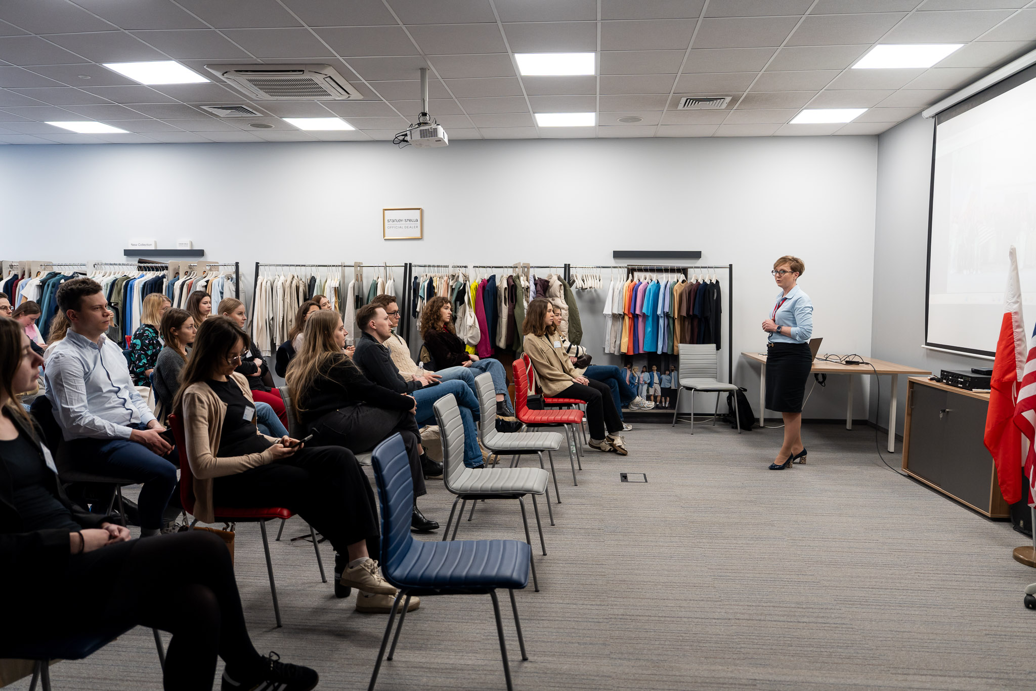 Szeroki plan na salę konferencyjną z uczestnikami siedzącymi w rzędach.