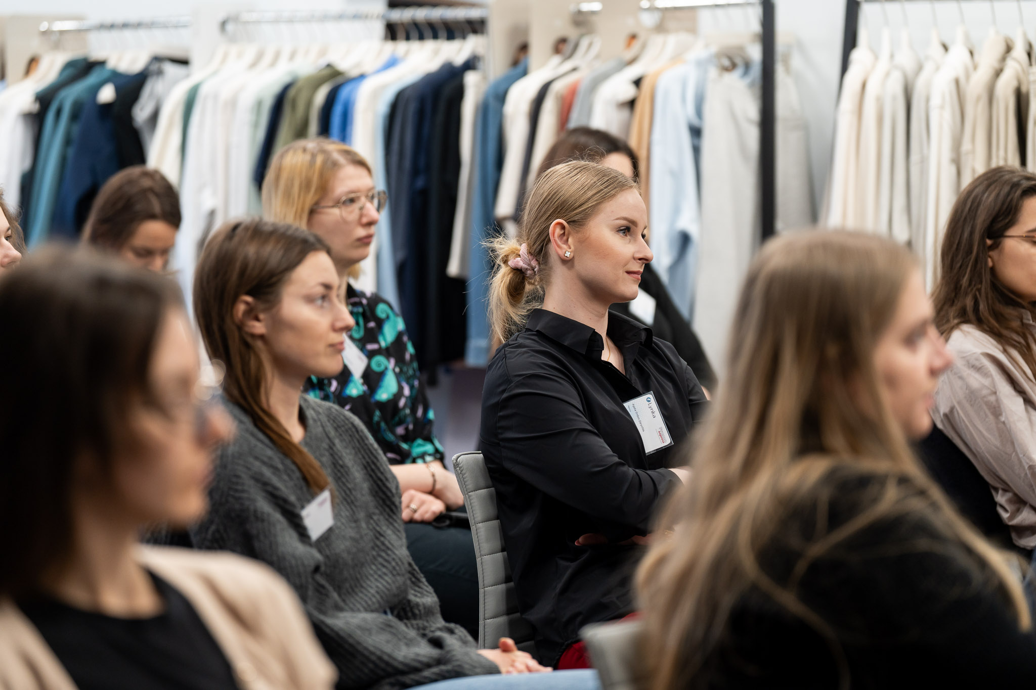 Zbliżenie na skupione twarze młodych os&oacute;b słuchających prelekcji.