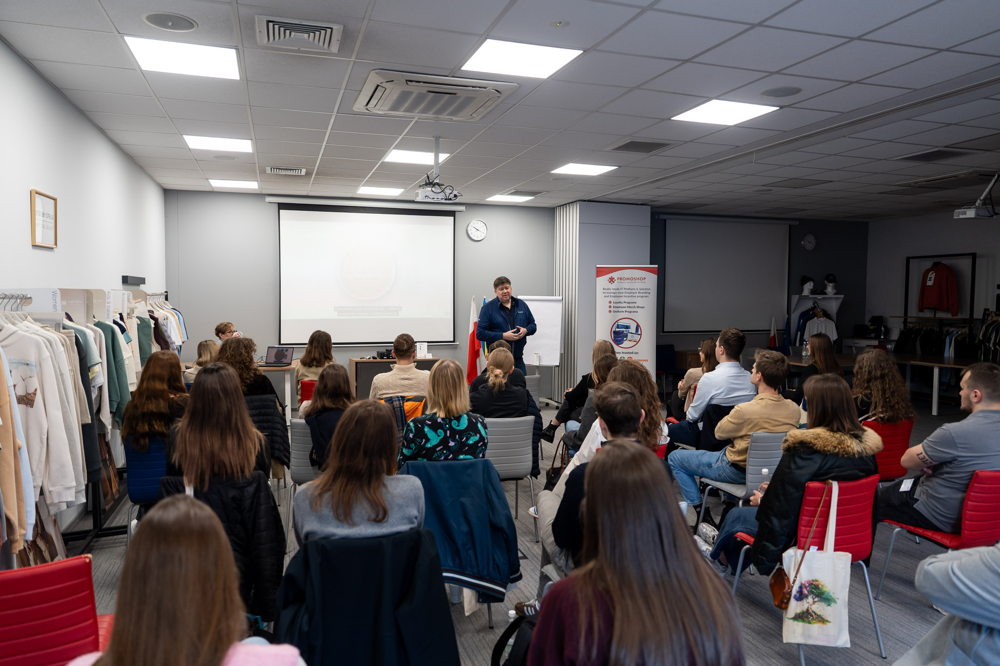 Widok z tyłu sali na publiczność wypełniającą salę konferencyjną.