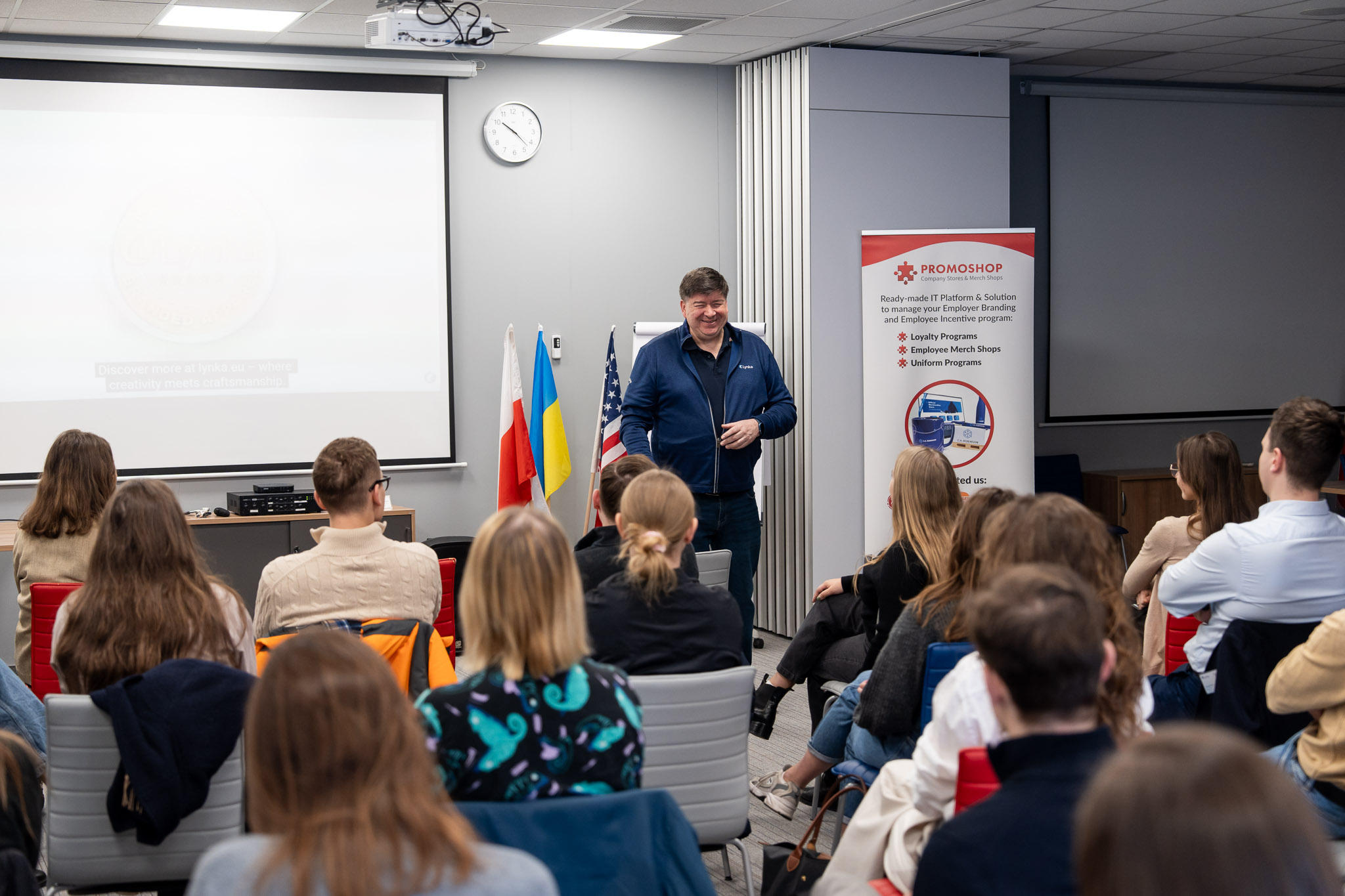 Prezentacja multimedialna wyświetlana na ekranie, uczestnicy w rzędach.