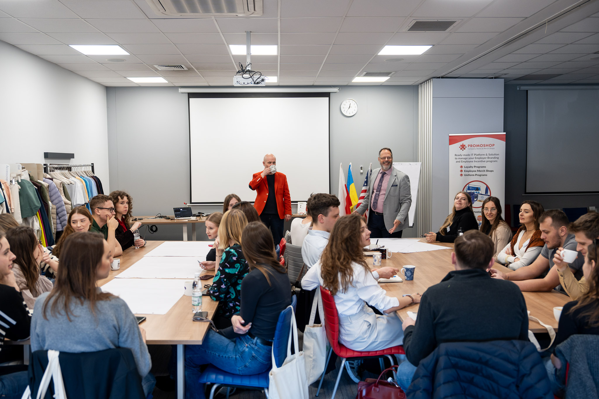 Praca zespołowa przy stołach, uczestnicy pochyleni nad arkuszami papieru.