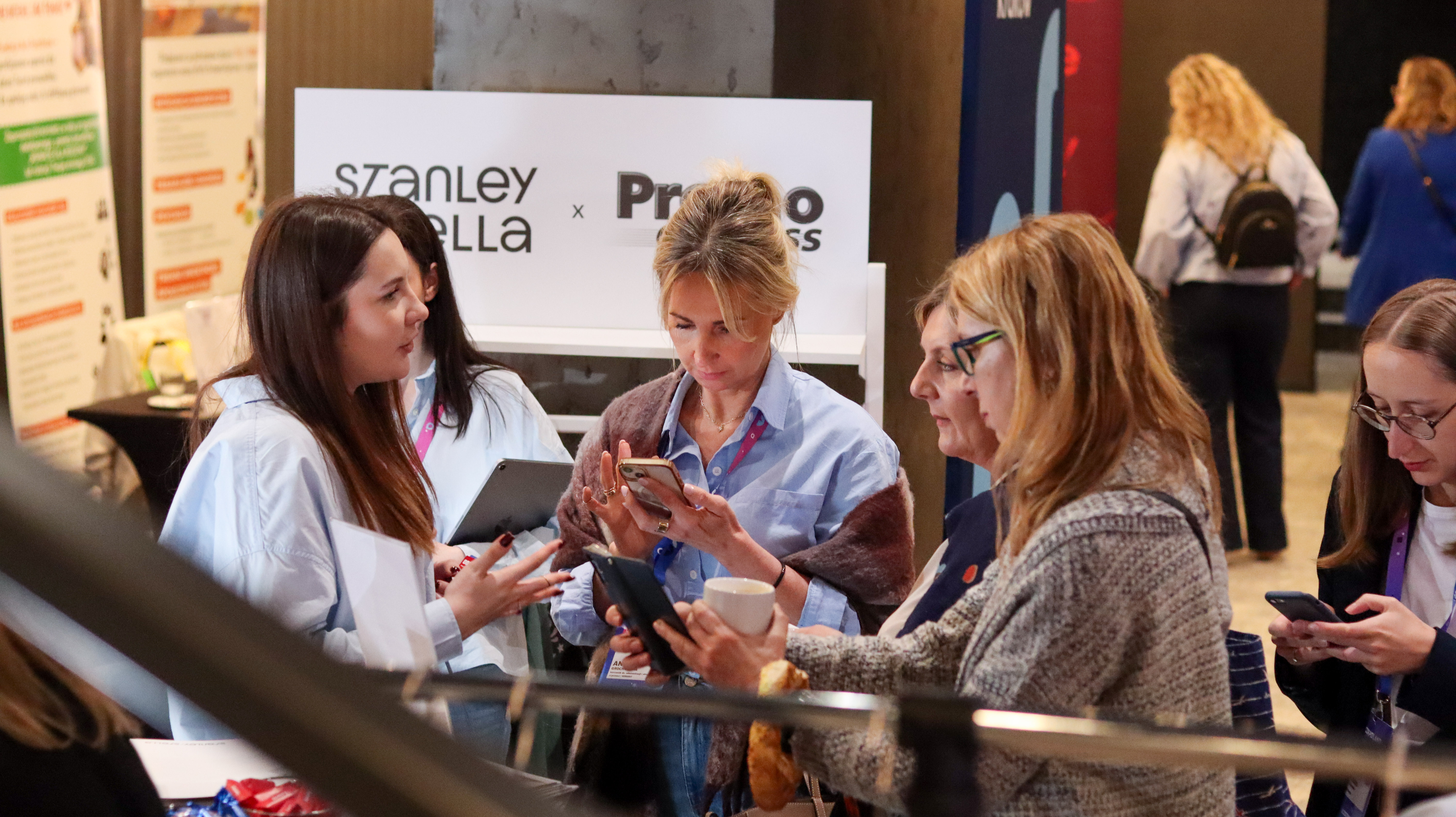 Trzy uśmiechnięte kobiety w błękitnych koszulach firmowych pozują wsp&oacute;lnie podczas wydarzenia CSR Poland 2026 na stoisku